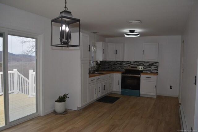 kitchen featuring wood counters, sink, stainless steel electric range oven, decorative light fixtures, and white cabinets