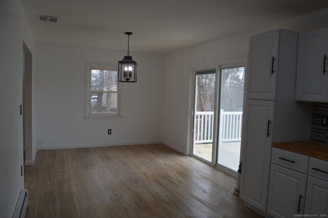 unfurnished dining area with light wood-type flooring and baseboard heating