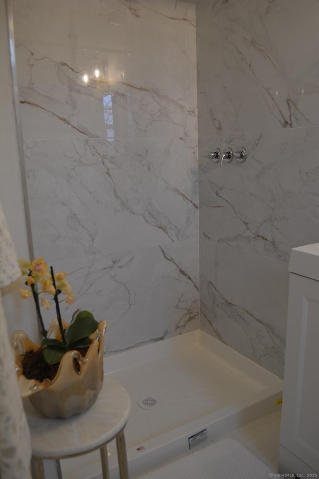 bathroom with tiled shower and vanity