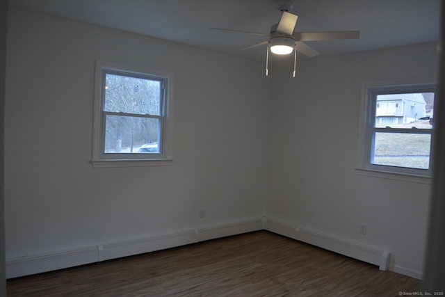 empty room featuring a baseboard heating unit, dark wood-type flooring, a wealth of natural light, and ceiling fan