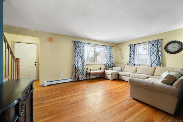 living room with a baseboard heating unit, a wealth of natural light, and light wood-type flooring