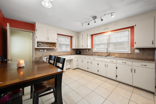 kitchen with backsplash, light tile patterned floors, sink, and white cabinets