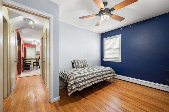 bedroom featuring a baseboard heating unit, ceiling fan, and light hardwood / wood-style flooring