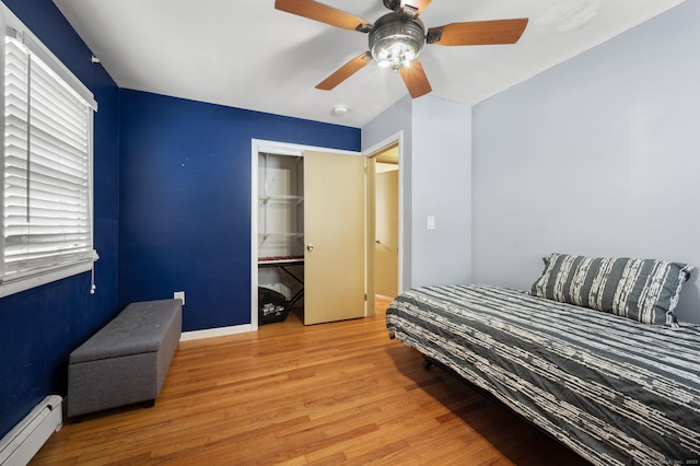 bedroom with baseboard heating, ceiling fan, and light hardwood / wood-style flooring