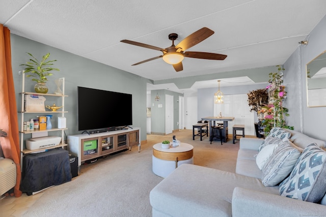 carpeted living room with ceiling fan with notable chandelier and a textured ceiling