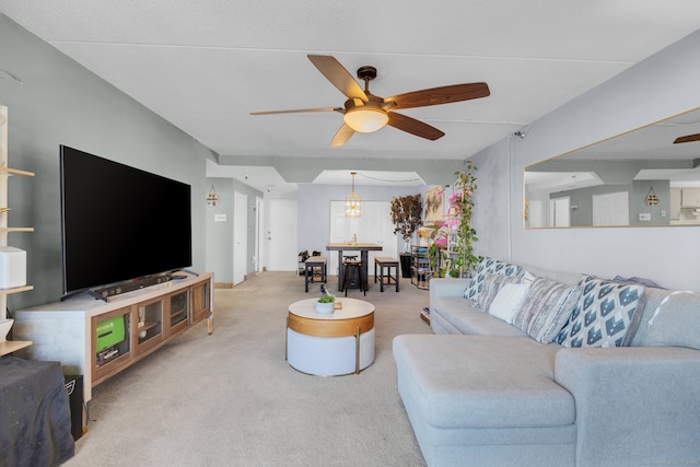 living room with ceiling fan with notable chandelier and light colored carpet