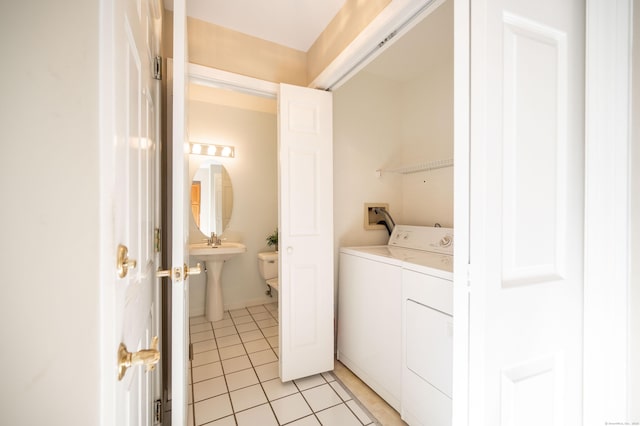 washroom with sink, light tile patterned floors, and washer and clothes dryer