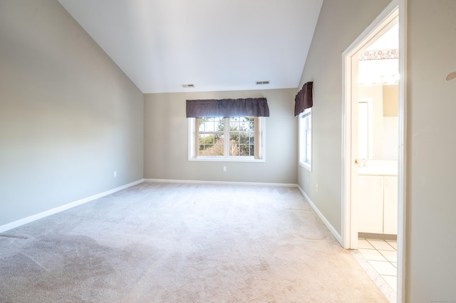 carpeted empty room featuring vaulted ceiling