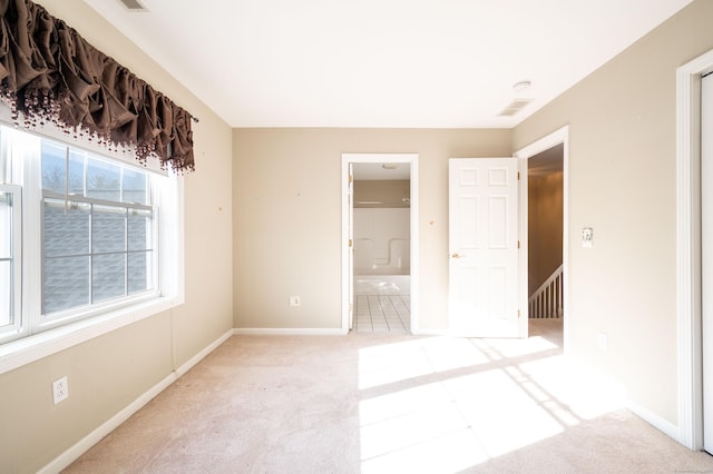 unfurnished bedroom featuring connected bathroom and light carpet