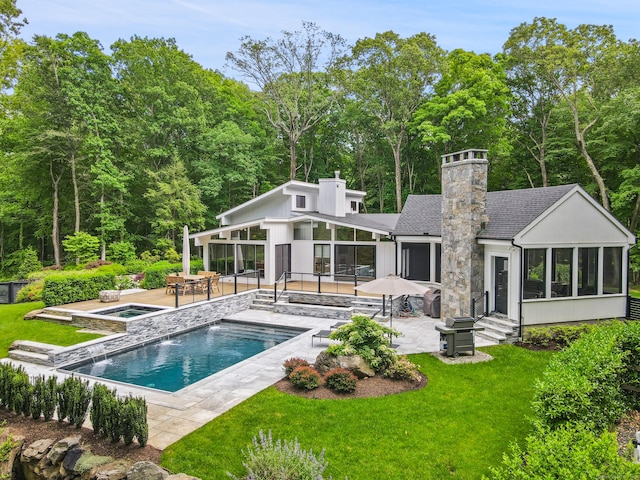 rear view of house with a swimming pool with hot tub, a lawn, a sunroom, and a patio