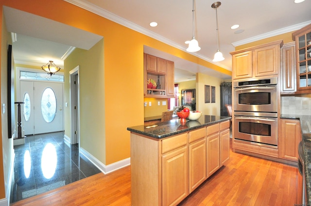 kitchen featuring backsplash, hanging light fixtures, ornamental molding, stainless steel double oven, and light brown cabinetry