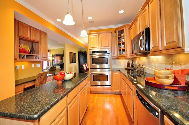 kitchen with pendant lighting, a center island, crown molding, light wood-type flooring, and appliances with stainless steel finishes