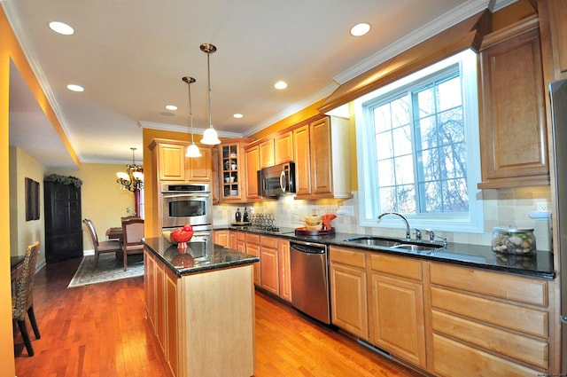 kitchen with pendant lighting, appliances with stainless steel finishes, a center island, sink, and light wood-type flooring