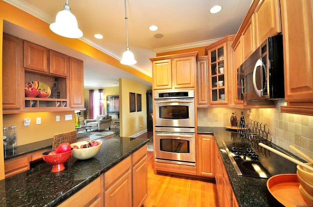 kitchen featuring appliances with stainless steel finishes, dark stone counters, and pendant lighting