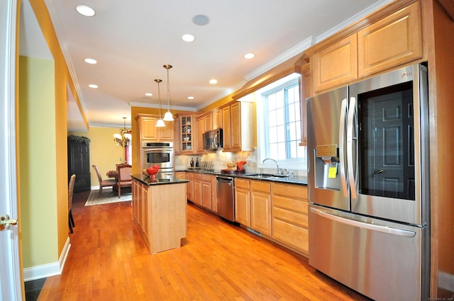 kitchen with appliances with stainless steel finishes, a center island, light wood-type flooring, hanging light fixtures, and sink