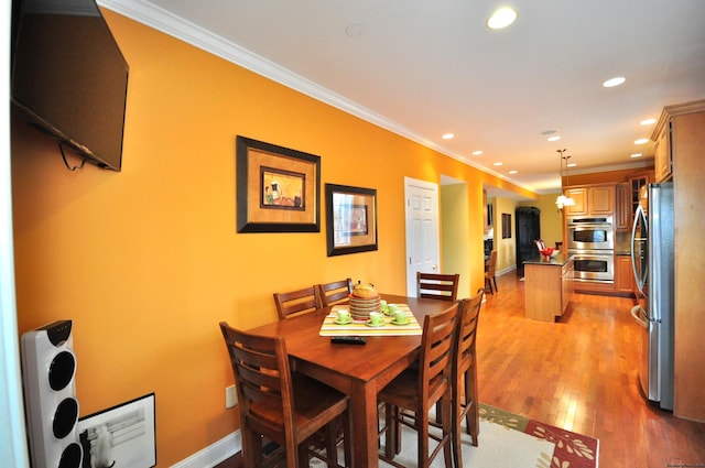 dining area featuring crown molding and light hardwood / wood-style flooring