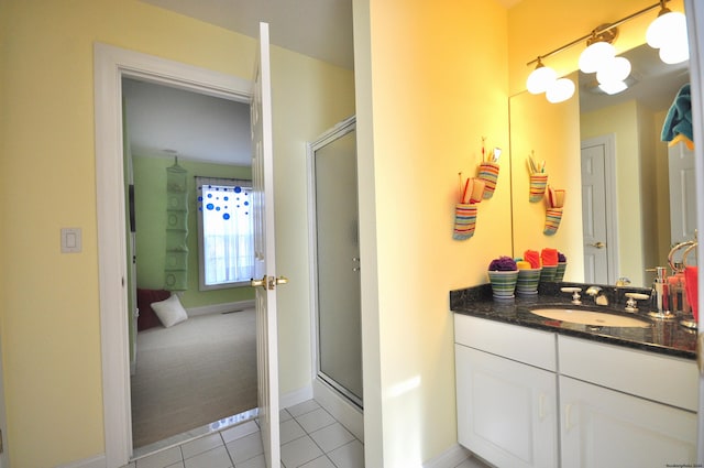 bathroom with a shower with shower door, vanity, and tile patterned flooring