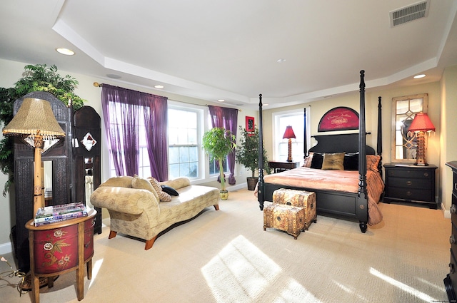 bedroom with a raised ceiling and light carpet