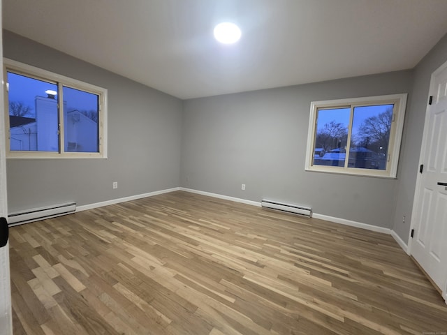 spare room with a baseboard heating unit, a baseboard radiator, wood finished floors, and baseboards