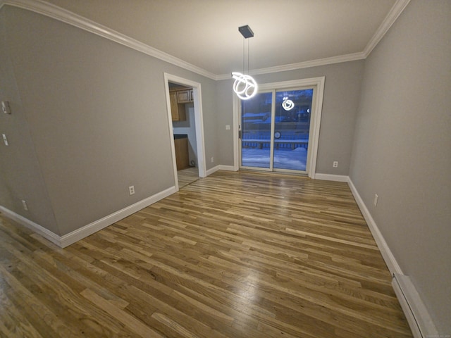 unfurnished dining area featuring crown molding, baseboards, and wood finished floors