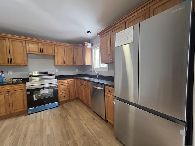 kitchen with dark countertops, appliances with stainless steel finishes, brown cabinets, and a sink