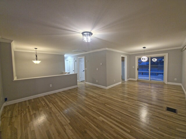 unfurnished living room featuring crown molding, baseboards, and wood finished floors