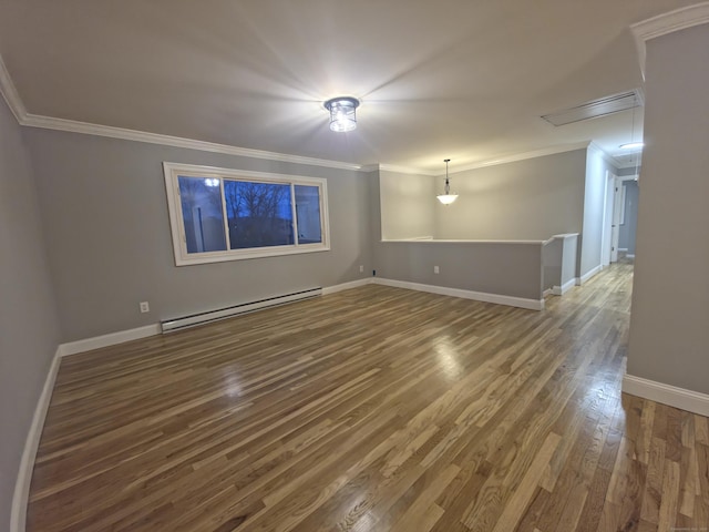 unfurnished room featuring wood finished floors, baseboards, baseboard heating, attic access, and crown molding