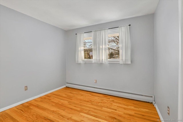 empty room featuring baseboard heating and light hardwood / wood-style floors