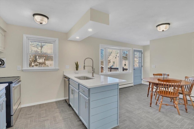 kitchen with sink, kitchen peninsula, baseboard heating, and appliances with stainless steel finishes