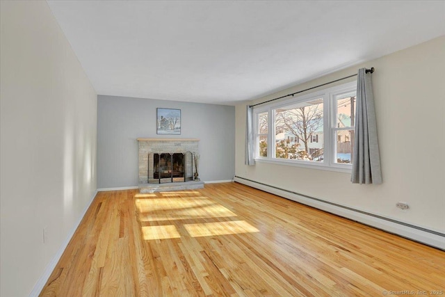 unfurnished living room with baseboard heating and hardwood / wood-style flooring