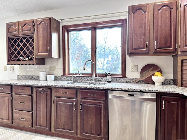 kitchen featuring stainless steel dishwasher, decorative backsplash, sink, and a textured ceiling