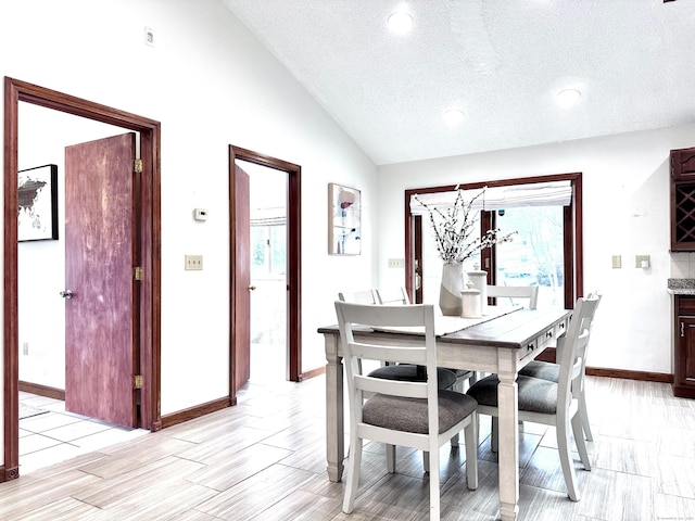 dining room with lofted ceiling and a textured ceiling