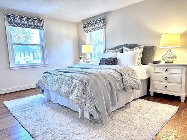 bedroom with dark wood-type flooring, a textured ceiling, and multiple windows