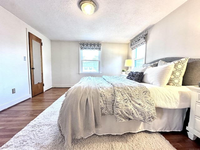 bedroom with a textured ceiling, dark hardwood / wood-style floors, and multiple windows