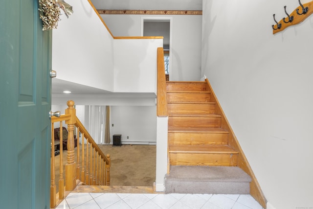 staircase with tile patterned floors and a high ceiling