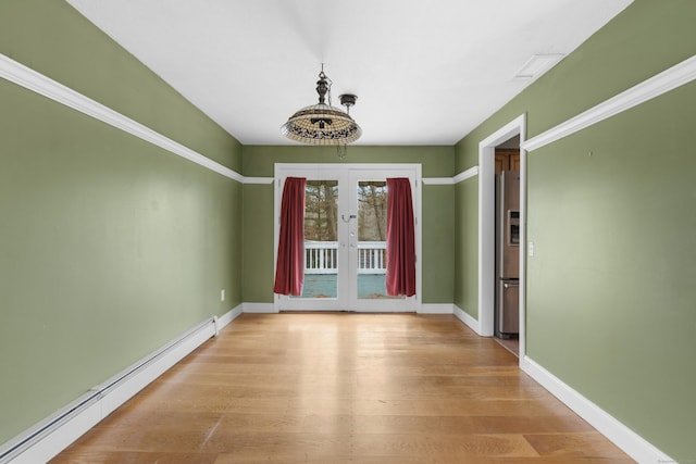 unfurnished dining area with light hardwood / wood-style floors, baseboard heating, and french doors