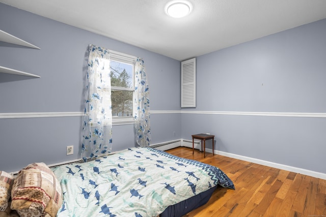 bedroom with a baseboard radiator and hardwood / wood-style floors