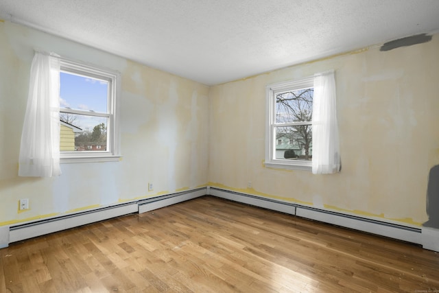 empty room with a textured ceiling and light hardwood / wood-style flooring