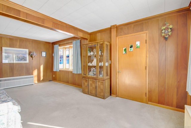 entryway with crown molding, radiator, light carpet, and wood walls