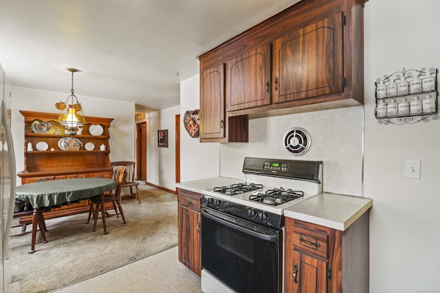 kitchen with pendant lighting, white gas stove, and light colored carpet