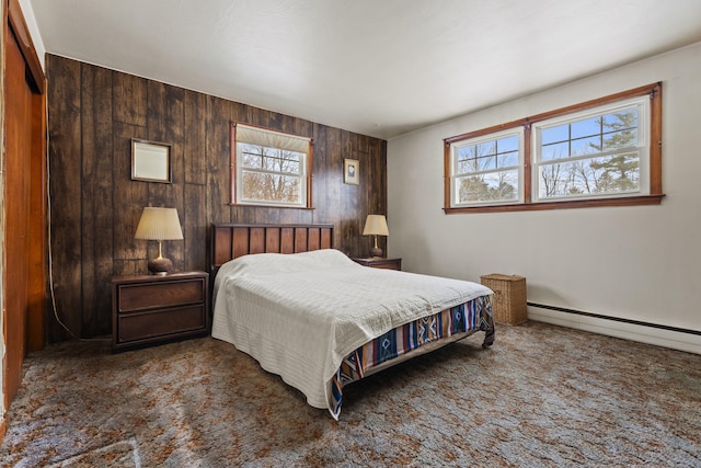 carpeted bedroom featuring multiple windows, a baseboard heating unit, and wooden walls