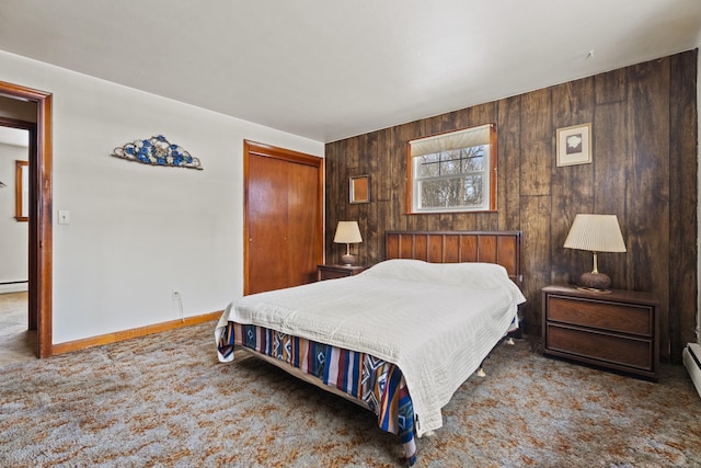 bedroom featuring wood walls, a baseboard radiator, a closet, and carpet flooring