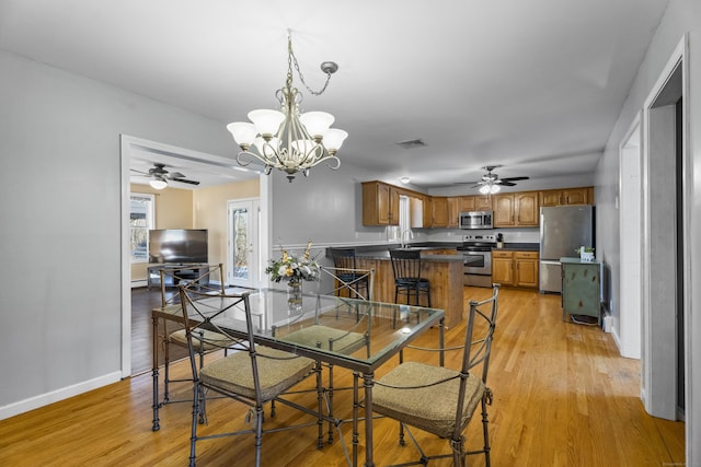 dining area featuring light wood-type flooring, sink, and ceiling fan with notable chandelier