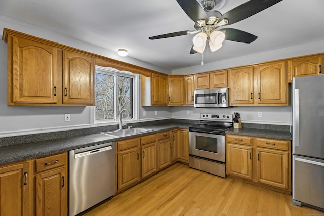 kitchen featuring ceiling fan, appliances with stainless steel finishes, light hardwood / wood-style flooring, and sink