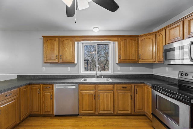 kitchen with light wood-type flooring, ceiling fan, appliances with stainless steel finishes, and sink