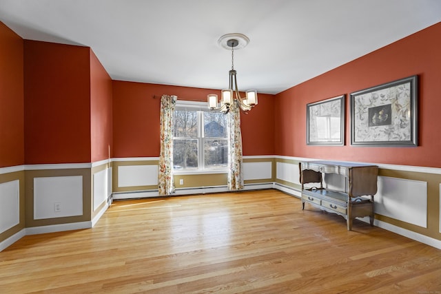 unfurnished dining area with light hardwood / wood-style flooring, a baseboard radiator, and a notable chandelier