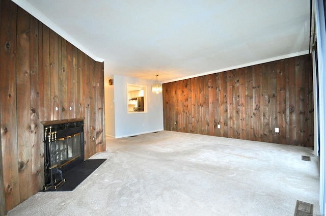 living room with crown molding, wooden walls, a chandelier, and dark carpet