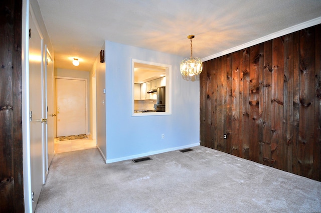 carpeted spare room featuring a chandelier