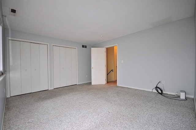 unfurnished bedroom with carpet floors and multiple closets