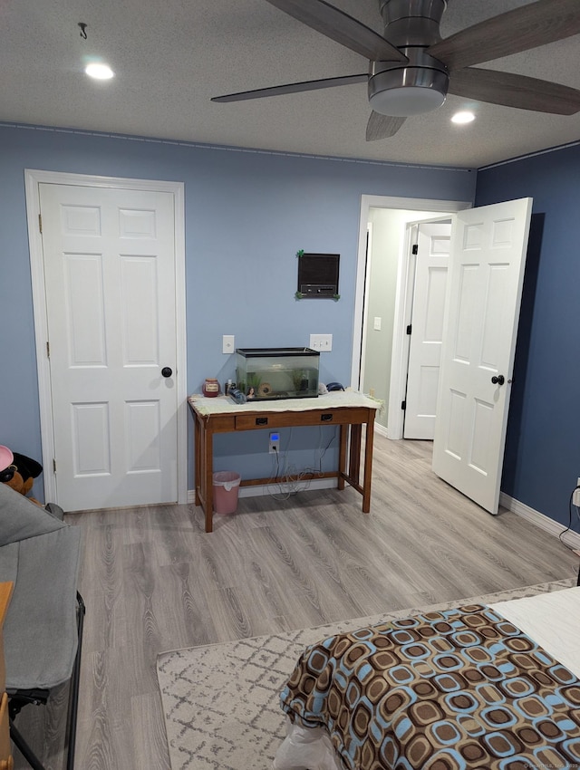 bedroom featuring ceiling fan, a textured ceiling, and light hardwood / wood-style flooring